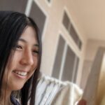 Heather Takenaga smiling and reading a book in the shade.