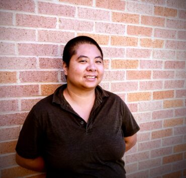 Ching-In Chen standing in front of a brick wall