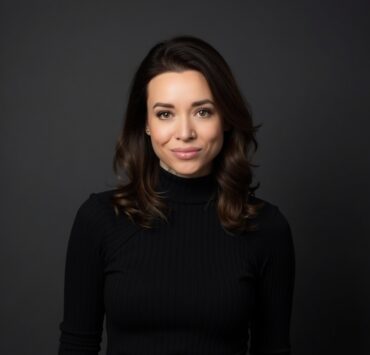 Image is a woman with shoulder-length dark hair wearing a black turtleneck.