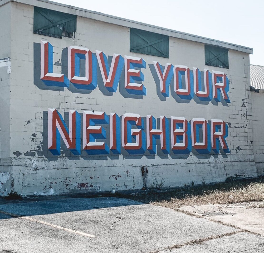 The phrase "Love Your Neighbor" painted on the side of a building