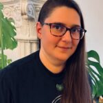 Interior headshot of Julia Bouwsma with decorative column and monstera plant in the background.