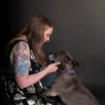 Tattooed woman in a party dress with grey pitbull